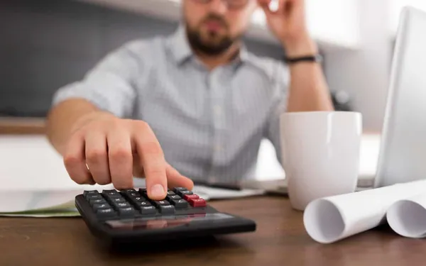 Hombre calculando la cancelación anticipada de su préstamo con calculadora