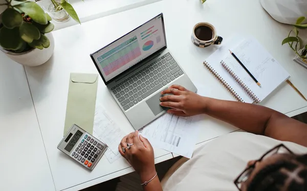 Persona revisando su cuenta en números rojos con portátil y calculadora