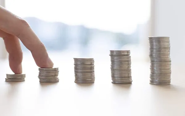 Dedo sobre pilas de monedas decrecientes, imagen del desapalancamiento financiero